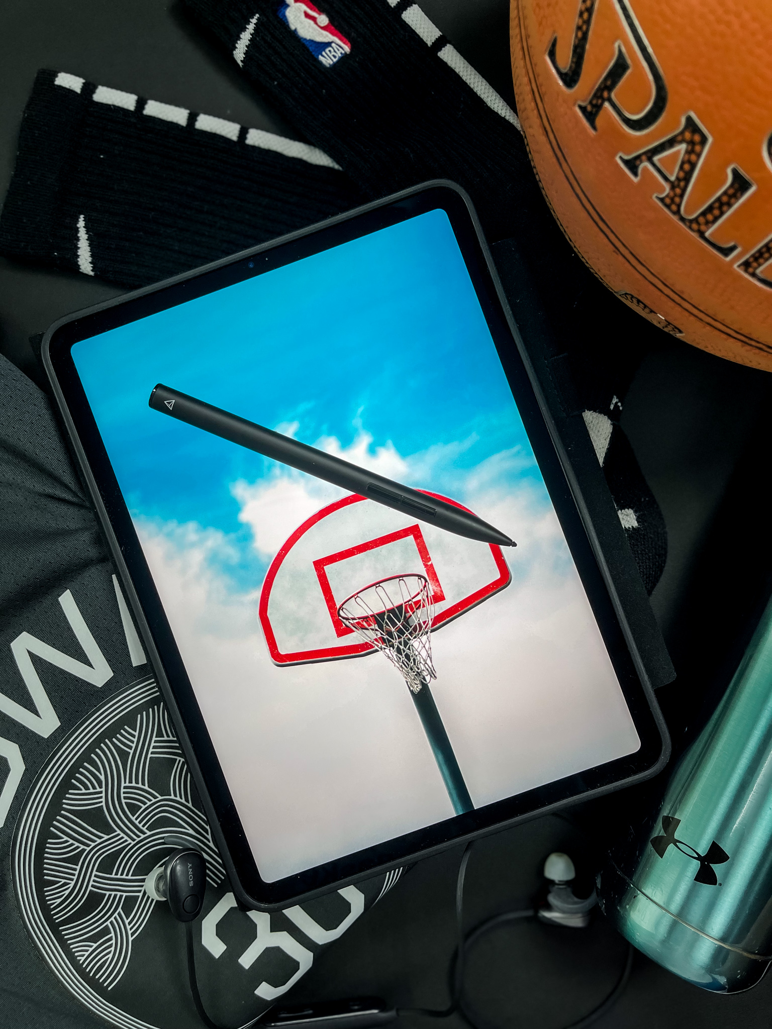 Basketball hoop against blue sky on iPad, sports flat-lay