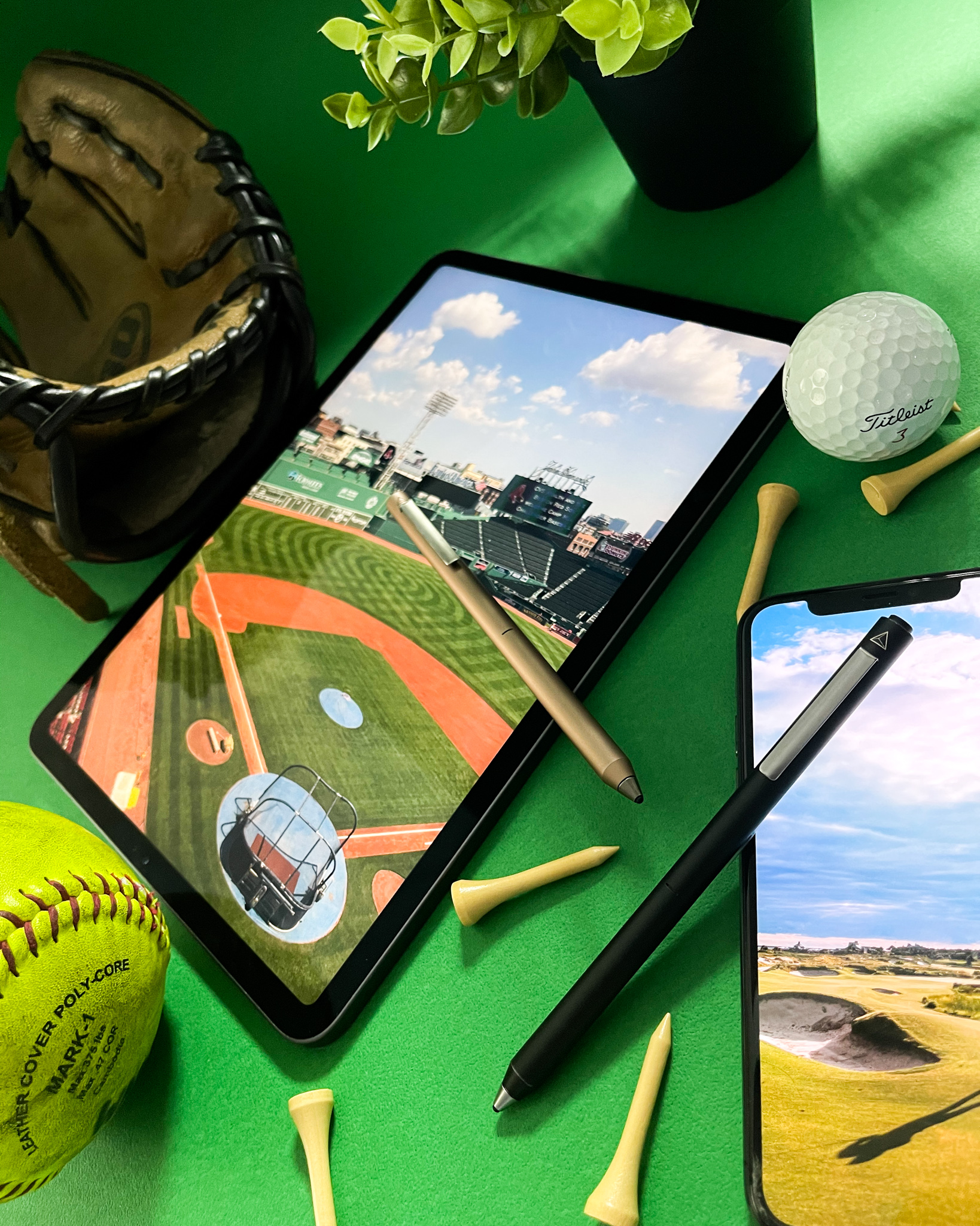Green flat-lay with baseball glove, golf ball and iPad showing a ballpark