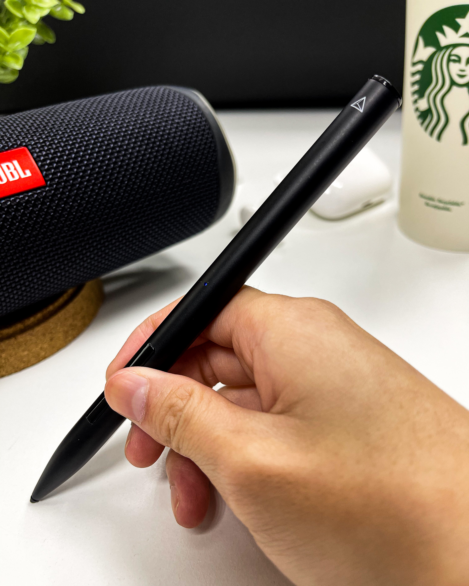 Hand holding the stylus in front of a JBL speaker