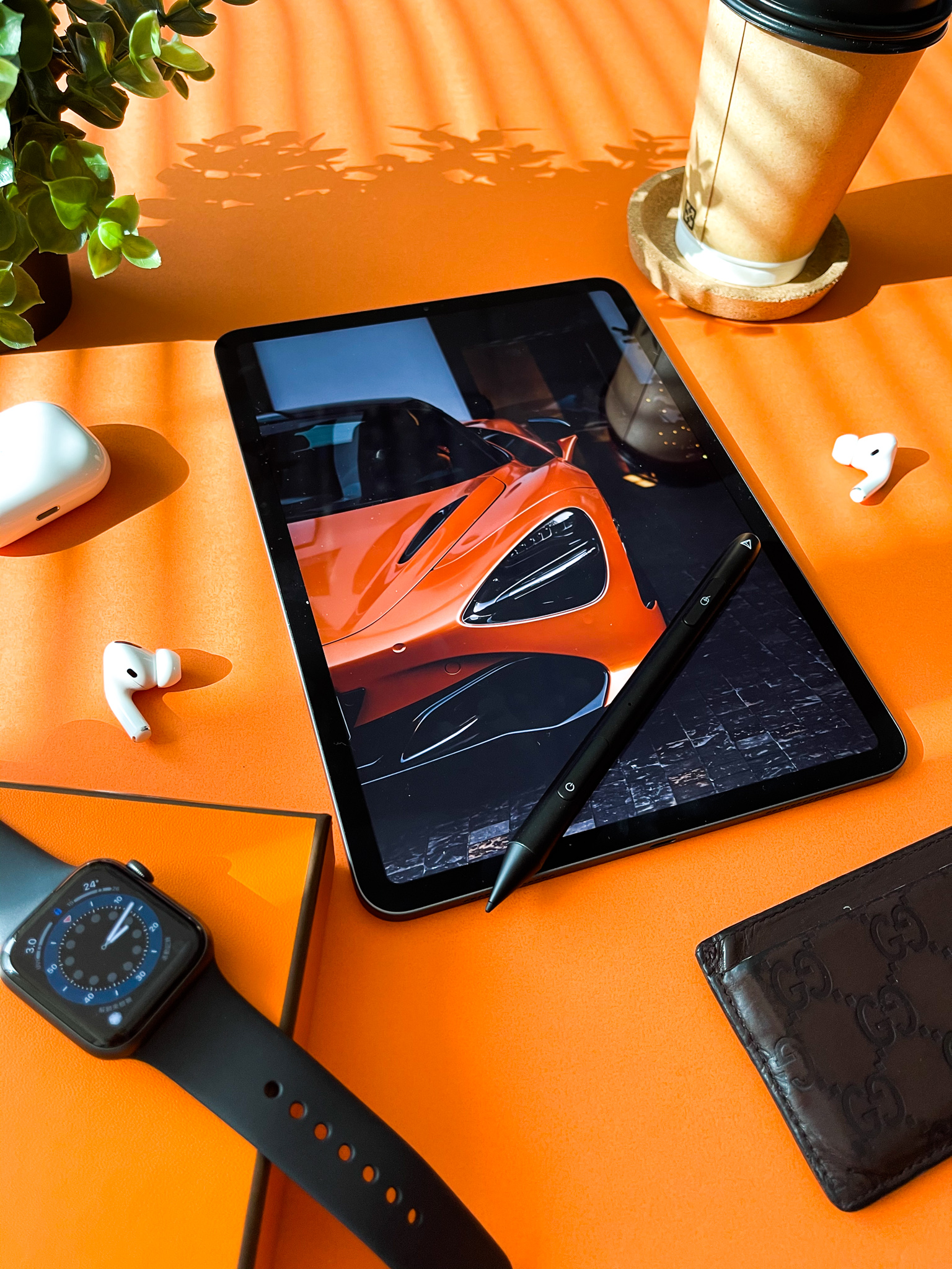 Orange McLaren on iPad, luxury desk flat-lay